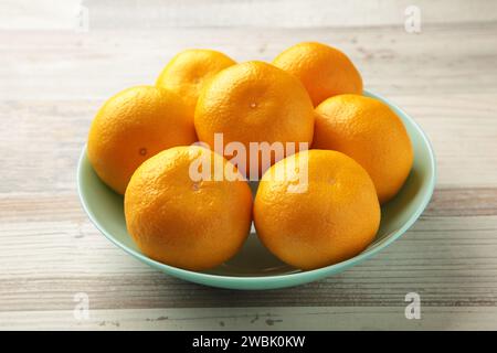 Fruits frais d'oranges mandarines sur le bol de menthe sur fond en bois gris. Vue de dessus. Banque D'Images