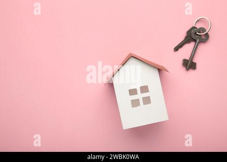 Maison de papier et clé sur fond rose avec espace de copie. Vue de dessus Banque D'Images