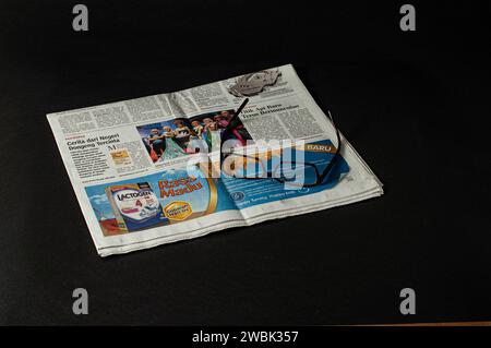 piles de journaux qui doivent être lus pour les nouvelles et les informations financières, et lunettes pour plus de clarté, photographiés sur un fond sombre Banque D'Images