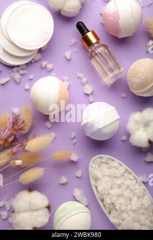 Composition avec bombes de bain, sel de mer, fleurs sèches sur fond violet Banque D'Images