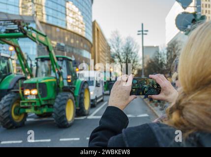 11 janvier 2024, Hesse, Francfort-sur-le-main : une femme filme la manifestation des agriculteurs avec son smartphone. Dans le cadre des manifestations des agriculteurs, environ 1 500 tracteurs devraient faire un rassemblement avec des tracteurs de différentes directions à la Festhalle dans le centre-ville, selon la ville. Les manifestations des agriculteurs se termineront par un rassemblement devant la salle des fêtes. Photo : Andreas Arnold/dpa Banque D'Images