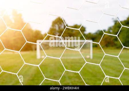 Vue lumineuse et ensoleillée du terrain de football à travers le filet Banque D'Images