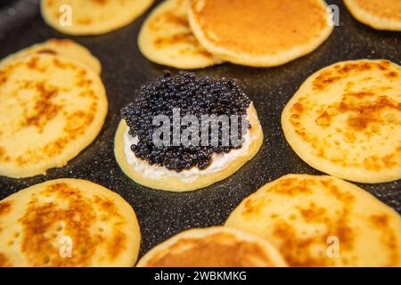 Blinis au caviar noir et fromage à la crème, sur un plat festif, mini crêpes, un élégant apéritif Banque D'Images