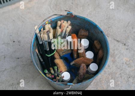 seau plein de pinceaux, pour peindre des murs et des toiles, des peintures, des cahiers, des objets, des outils de base pour travailler à l'école, des cours, des laboratoires. Banque D'Images