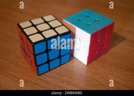 Deux cubes de rubik sur un bureau montrant des côtés rouge blanc et bleu Banque D'Images
