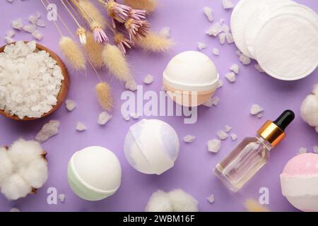 Bombes de bain d'arôme dans la composition de spa avec des fleurs sèches et du sel sur fond violet. Vue de dessus Banque D'Images