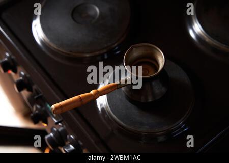 Un homme préparant du café noir sur une cuisinière électrique. Préparez du café dans une cafetière turque. Banque D'Images