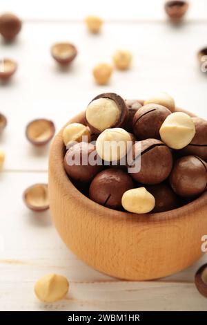 Noix de macadamia pelées dans un bol en bois sur fond blanc. Photo verticale. Vue de dessus Banque D'Images