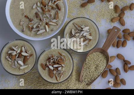 Délicieux Millet Proso Kheer dans un bol en verre, orné d'amandes croquantes, mettant en valeur un dessert nutritif. Autour du bol est un tas généreux o Banque D'Images