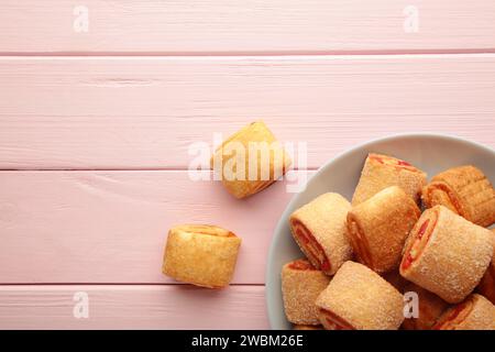 Biscuits faits maison, mini rouleaux avec confiture d'abricot sur fond rose. Vue de dessus. Banque D'Images