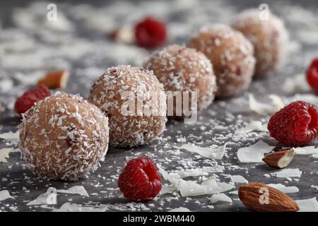 Truffes maison. Bonbons ronds. Truffe a amandes. Copeaux de noix de coco. Boules de chocolat sucré remplies d'amandes et de framboises sur un fond sombre Banque D'Images