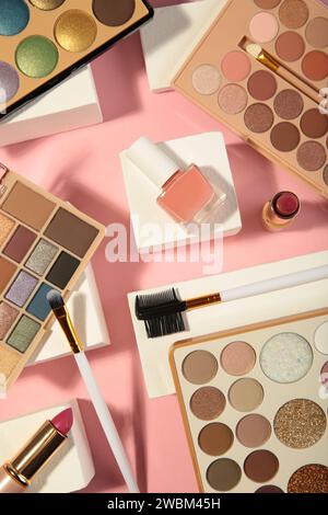 Différents produits de maquillage de luxe sur podium géométrique rose sur fond bleu. Contexte de la présentation de la marque et de l'emballage. Beauté et maquillage pr Banque D'Images