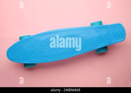 Penny Skate board bleu avec des roues bleues sur fond rose. Vue de dessus Banque D'Images