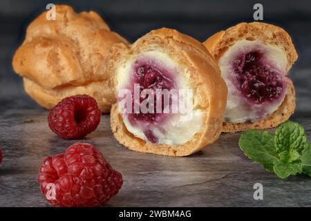 Délicieux profiteroles. Avec de la crème de framboise sur un fond gris. Concept de pâtisserie maison. Photo est utilisé pour le menu ou la publicité. Gros plan Banque D'Images