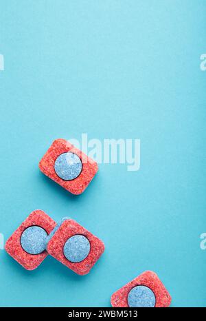 Comprimés rouges et bleus pour lave-vaisselle. Détergents pour l'hygiène domestique. Capsules de lave-vaisselle sur fond bleu. Vue de dessus Banque D'Images