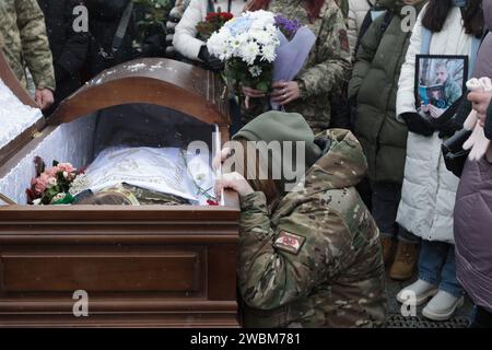 KIEV, UKRAINE - le 11 JANVIER 2024 - Une femme s'agenouille près du cercueil alors qu'elle rend ses derniers hommages au poète et militaire ukrainien Maksym Kryvtsov (Dali), décédé sur la ligne de front le 7 janvier 2024 à Maidan Nezalezhnosti à Kiev, capitale de l'Ukraine. Banque D'Images