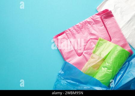 Beaucoup de sacs en plastique colorés roulent sur un fond bleu. Vue de dessus. Banque D'Images