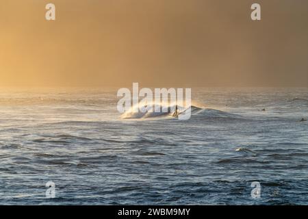 Les vagues dorées du parc Ho'okipa Beach offrent un rêve aux surfeurs alors que le soleil de Maui projette sa lueur finale. Banque D'Images