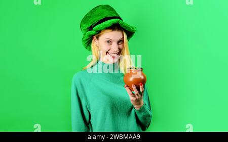 Bonne journée de Patrick. Pot d'argent pour la fête de Patrick. Femme souriante en chapeau vert Leprechaun avec pot d'or. Traditions de la Saint Patrick Day Banque D'Images