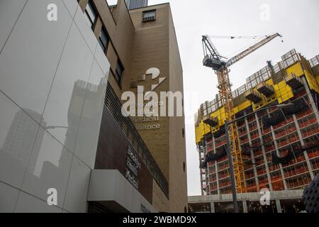 Une vue architecturale d'un immeuble moderne de grande hauteur avec plusieurs grues au premier plan devant un chantier de construction Banque D'Images