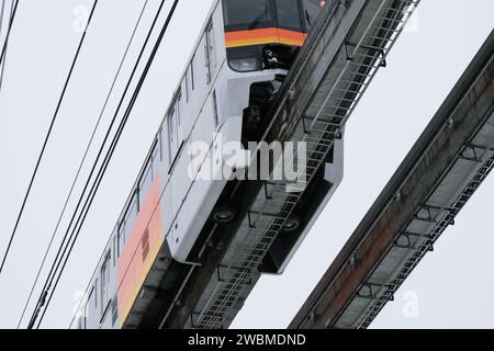 Train monorail en mouvement sur voie surélevée avec fond urbain, mettant en valeur les transports publics modernes. Banque D'Images