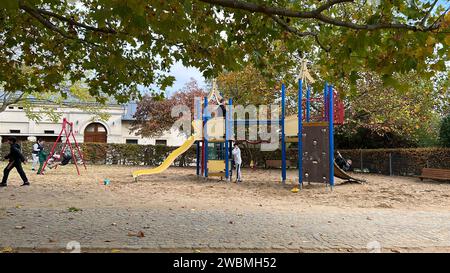 Une aire de jeux pour enfants aux couleurs vives entourée d'herbes vertes luxuriantes et d'arbres située au centre d'un parc public Banque D'Images