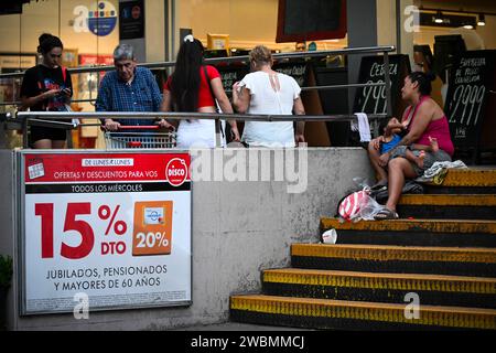 Buenos Aires, Argentine. 10 janvier 2024. Une femme avec un enfant dans les bras demande des dons à l’entrée d’un supermarché. Les prix des denrées alimentaires ont augmenté de 20 pour cent dans la capitale Argentine en décembre 2023. Crédit : Martin Cossarini//dpa/Alamy Live News Banque D'Images