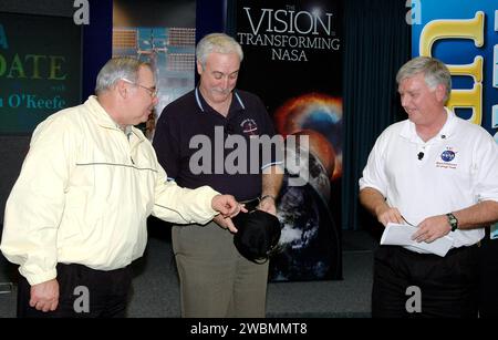 CENTRE SPATIAL KENNEDY, FLA. - L’administrateur de la NASA Sean O’Keefe (au centre) reçoit un chapeau d’impact profond dans l’Auditorium du site de presse suite à son rapport aux employés sur l’état de l’Agence. Il est accompagné sur scène par le directeur du centre Jim Kennedy (à droite). La mise à jour a été diffusée en direct via NASA Television. O'Keefe s'est concentré sur les réalisations de 2004 et les objectifs fixés pour 2005. Ses remarques ont souligné les étapes franchies dans la Vision for Space exploration de la NASA, y compris le lancement de la mission d'impact profond chassant les comètes et l'atterrissage de la sonde Huygens sur Titan, la lune de Jupiter, tous deux oc Banque D'Images