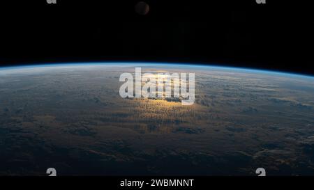 Le 18 juillet 2020, l'ISS a survolé le Pacifique Sud entre l'Australie et l'Amérique du Sud, la lumière du soleil se reflétant sur la surface partiellement nuageuse de l'océan le long de sa trajectoire orbitale. Banque D'Images