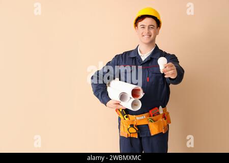 Électricien masculin avec ampoule et plans de maison sur fond beige Banque D'Images