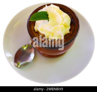 Le dessert délicat de flan est servi dans un bol miniature décoré de feuilles de menthe fraîche parfumée Banque D'Images