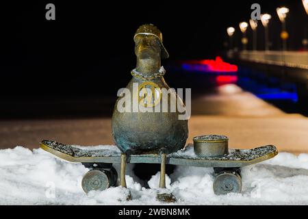 Sur le quai de Kolobrzeg, « Marian », une sculpture de mouette, se dresse gracieusement au milieu d'une nuit d'hiver enchantée. La jetée enneigée renforce le b serein Banque D'Images