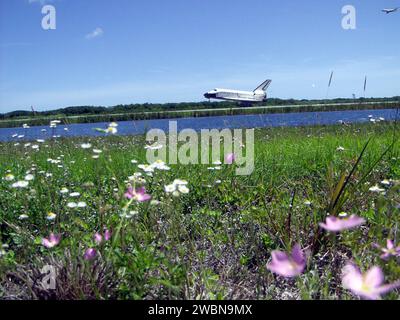 La navette spatiale Atlantis atterrit sur la piste 33 au Kennedy Space Center, déployant sa goulotte pour compléter la mission STS-110 de 10 jours et 19 heures à destination de la Station spatiale internationale. L'équipage est revenu après avoir livré et installé la ferme S0 pour soutenir les systèmes de refroidissement et d'alimentation de l'ISS, tandis qu'un avion de poursuite suivait l'atterrissage de l'orbiteur. Banque D'Images