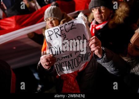 Varsovie, Pologne, 11 janvier 2024. Le manifestant tient une bannière qui dit "loin avec la dictature" alors que des foules de personnes, dirigées par droit et Justice (Prawo i Sprawiedliwość - pis) dirigeants de partis politiques protestent devant le bâtiment du Parlement polonais contre les changements dans les médias publics en Pologne et dans la protection de la démocratie - disent les politiciens pis. Le parti droit et Justice a régné en Pologne pendant 8 ans jusqu'à ce qu'ils perdent les dernières élections en octobre 2023. Le parti devient maintenant une force d'opposition de droite contre une coalition dirigeante plus centriste et libérale, dont la principale force politique est la Coalition civique Banque D'Images