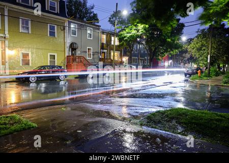 Rues humides la nuit pendant une tempête de pluie intense dans le secteur résidentiel de North End Halifax, Nouvelle-Écosse. Longue exposition avec la lumière de traînée des voitures qui passent Banque D'Images