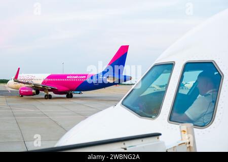 Un pilote d'avion est assis dans le cockpit et l'avion Wizzair sur le fond. Janvier 2024, Prague, République tchèque Banque D'Images