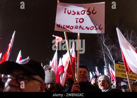 Varsovie, Pologne, 11 janvier 2024. Foules de gens, tenant des drapeaux nationaux polonais et une bannière qui disent "Tusk-ality is immorality", dirigée par droit et Justice (prawo i Sprawiedliwość - pis) les dirigeants des partis politiques protestent devant le bâtiment du Parlement polonais contre les changements dans les médias publics en Pologne et dans la protection de la démocratie - disent les politiciens du pis. Le parti droit et Justice a régné en Pologne pendant 8 ans jusqu'à ce qu'ils perdent les dernières élections en octobre 2023. Le parti devient maintenant une force d'opposition de droite contre une coalition dirigeante plus centriste et libérale, où la principale force politique Banque D'Images