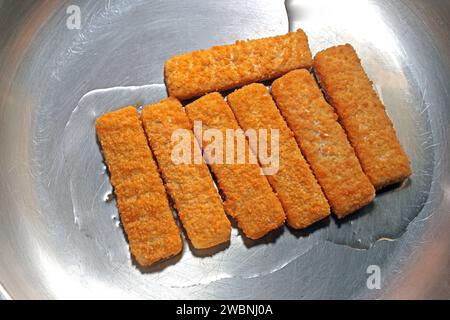 Fisch als Lebensmittel Fischstäbchen liegen während der Zubereitung in einer Edelstahlpfanne *** poisson comme aliment les doigts de poisson sont placés dans une poêle en acier inoxydable pendant la préparation Banque D'Images