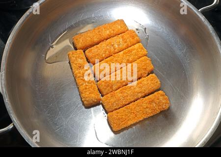 Fisch als Lebensmittel Fischstäbchen liegen während der Zubereitung in einer Edelstahlpfanne *** poisson comme aliment les doigts de poisson sont placés dans une poêle en acier inoxydable pendant la préparation Banque D'Images