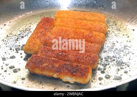 Fisch als Lebensmittel Fischstäbchen liegen während der Zubereitung in einer Edelstahlpfanne *** poisson comme aliment les doigts de poisson sont placés dans une poêle en acier inoxydable pendant la préparation Banque D'Images