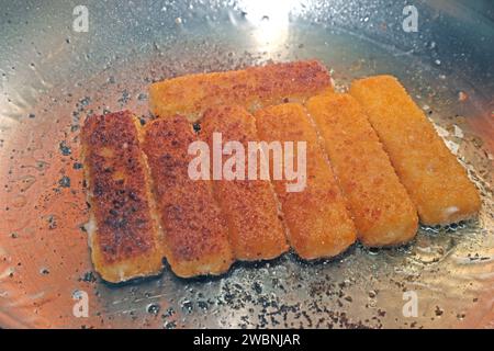 Fisch als Lebensmittel Fischstäbchen liegen während der Zubereitung in einer Edelstahlpfanne *** poisson comme aliment les doigts de poisson sont placés dans une poêle en acier inoxydable pendant la préparation Banque D'Images