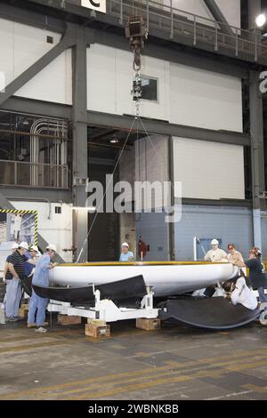 Les techniciens du Kennedy Space Center Vehicle Assembly Building de la NASA fixent le bouclier thermique retiré du véhicule d'essai au sol Orion sur une plate-forme d'attente. Le véhicule d'essai sera transféré au Langley Research Center pour des essais d'eau et est utilisé par le programme de développement et d'exploitation des systèmes au sol pour la fabrication, l'assemblage et l'empilement simulés. Orion est conçu pour l'exploration spatiale profonde avec équipage avec des capacités d'avortement d'urgence et de rentrée en toute sécurité. Banque D'Images