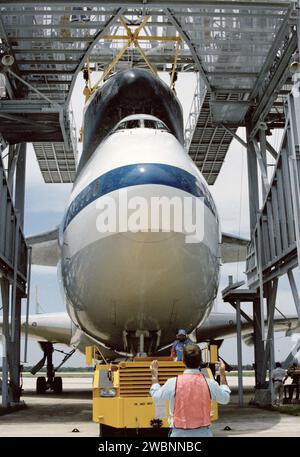 La navette spatiale Discovery retourne au Kennedy Space Center au sommet du porte-navette après la mission STS-31. Les techniciens John Goleno et Peter Seidel guident l'avion et l'orbiteur dans le dispositif de démantèlement à l'installation d'atterrissage de la navette pour le traitement post-mission. Banque D'Images