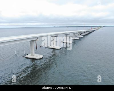 Dans cette vue aérienne, les équipages d’Orion Marine Construction travaillent à compléter la travée en direction ouest du pont Indian River, tandis que le trafic quotidien se déplace le long des voies améliorées en direction est du pont menant au Kennedy Space Center de la NASA en Floride le lundi 27 novembre 2023. Le pont traverse la lagune de la rivière Indian et relie Kennedy et la station spatiale Cape Canaveral au continent via State Road 405/NASA Causeway à Titusville. Le nouveau pont de grande hauteur sert d'entrée et de sortie principale au centre spatial pour les employés et les visiteurs. Les nouvelles travées de pont remplacent une paire o Banque D'Images