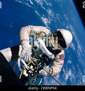 S65-30431 (3 juin 1965) --- l'astronaute Edward H. White II, pilote de la mission orbitale terrestre de quatre jours Gemini IV, flotte dans la gravité zéro de l'espace à l'extérieur du vaisseau spatial Gemini IV. Derrière lui se trouve la Terre bleue brillante et sa couverture nuageuse blanche. White porte une combinaison spatiale spécialement conçue ; et la visière du casque est plaquée or pour le protéger contre les rayons non filtrés du soleil. Il porte également un pack d'oxygène d'urgence. Il est attaché au vaisseau spatial par une ligne ombilicale de 25 pieds et une ligne d'attache de 23 pieds, toutes deux enveloppées dans du ruban doré pour former un cordon. Dans sa main gauche se trouve un soi tenu à la main Banque D'Images