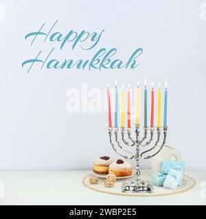 Joyeux Hanukkah. Menorah, beignets, cadeaux et dreidels sur la table blanche Banque D'Images