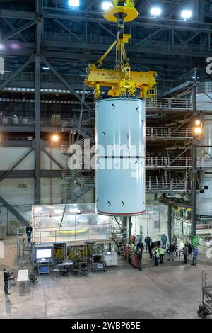 Dans High Bay 4 du Vehicle Assembly Building du Kennedy Space Center de la NASA en Floride, une grue déplace des segments de lanceur de fusée solide du Space Launch System (SLS) vers une plate-forme lors d’un exercice d’entraînement le 8 janvier 2020. Une équipe d’ingénieurs d’exploration Ground Systems et d’opérateurs de grues et de techniciens avec l’entrepreneur Jacobs pratiquent des manœuvres de levage, de déplacement et d’empilage, en utilisant de l’équipement de soutien au sol important pour former les employés et certifier que tout l’équipement fonctionne correctement. Les détecteurs de trajectoire du booster sont des répliques inertes à grande échelle du matériel du booster qui le fera Banque D'Images