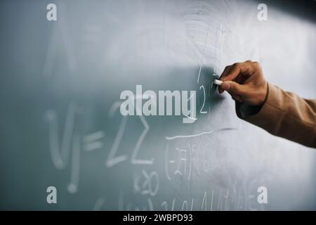 Gros plan, main et écriture sur un tableau noir, formule et enseignement avec système, processus et geek. Zoom, personne et professeur avec craie, apprentissage et maths Banque D'Images