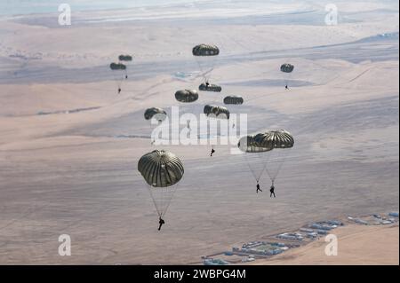 Les opérateurs des Forces spéciales interarmées qatariennes déploient leurs parachutes au-dessus d’un emplacement non divulgué dans la zone de responsabilité du Commandement central des États-Unis dans le cadre de l’opération Desert Redhawk 2, 25 décembre 2023. Plus de 50 opérateurs de la QJSF et parachutistes de l'armée américaine ont effectué une formation aérienne et aérienne dans le cadre de l'opération Desert Redhawk 2, leur permettant de maintenir leur état de préparation et leur expertise et de renforcer les relations entre les forces américaines et qatariennes. (Photo de l'US Air Force par le sergent d'état-major Caleb Roland) Banque D'Images