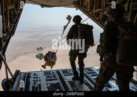 Les opérateurs des forces spéciales interarmées qatariennes effectuent un saut de ligne statique depuis un C-130J Super Hercules, affecté au 61st Expeditionary Airlift Squadron, lors de l'opération Desert Redhawk 2 au-dessus d'un emplacement non divulgué dans la zone de responsabilité du commandement central des États-Unis le 25 décembre 2023. L'opération Desert Redhawk 2 est un exercice de formation de la coalition aéroportée et aérienne qui met l'accent sur le maintien des livraisons aériennes à l'appui des fonctions de combat en cours. (Photo de l'US Air Force par le sergent d'état-major Caleb Roland) Banque D'Images